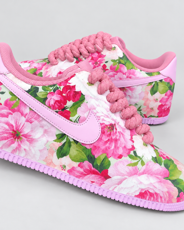 Pink floral custom sneakers with pink rope laces on a light gray studio background