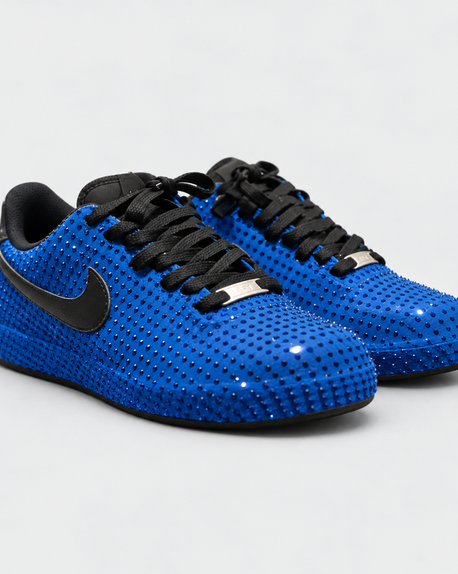 Royal blue rhinestone sneakers with black laces on a light gray studio background
